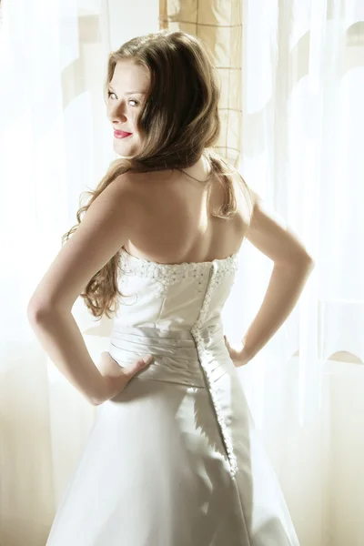 微笑着年轻貌美的新娘在自然光线中的窗口 免版税图库图片