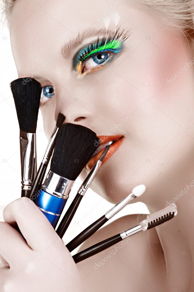 Beautiful woman with makeup brushes