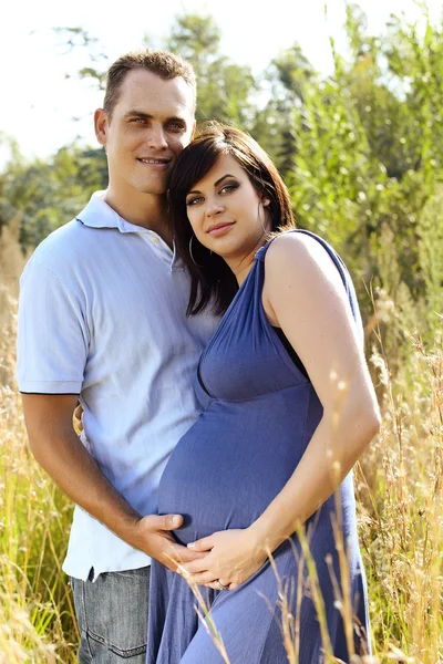 Мужчина и беременная жена в поле — стоковое фото