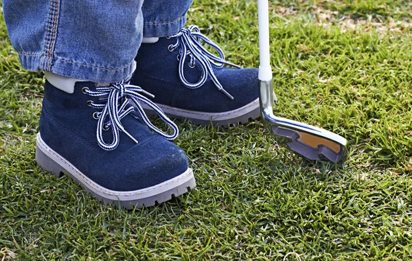 Boy shoes and golf club on grass — Stock Photo, Image