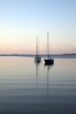 Two yachts lined up at the anchorage clipart