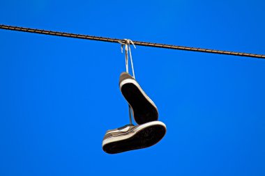 Tennis shoes hanging from a power line clipart