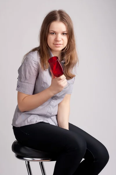 Uma menina em uma camiseta vermelha brilhante e um copo sentado — Fotografia de Stock