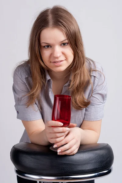 Ein Mädchen in einem knallroten T-Shirt und einem Glas sitzend — Stockfoto