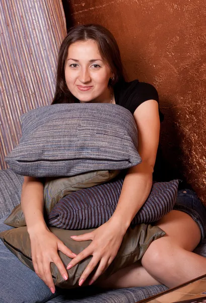 Meisje zit leunend op een heleboel kussens — Stockfoto