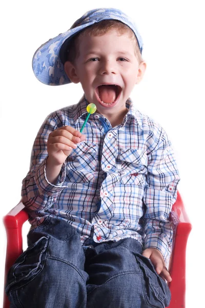 Jongen met een open mond met een lolly in zijn hand op een lichte achtergrond — Stockfoto