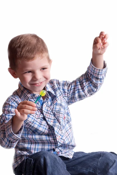 Smiling boy with a lollipop in his hand — Stock Photo, Image