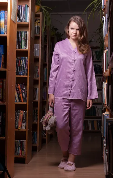 Flicka i pyjamas och tofflor på natten i biblioteket — Stockfoto