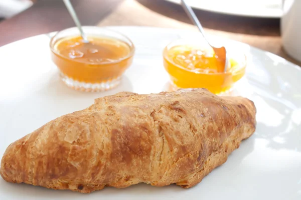 Großes Croissant auf einem Teller mit einer Portion Marmelade — Stockfoto
