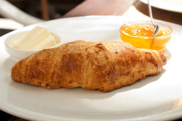 Large croissant on a plate with a portion of jam — Stock Photo, Image