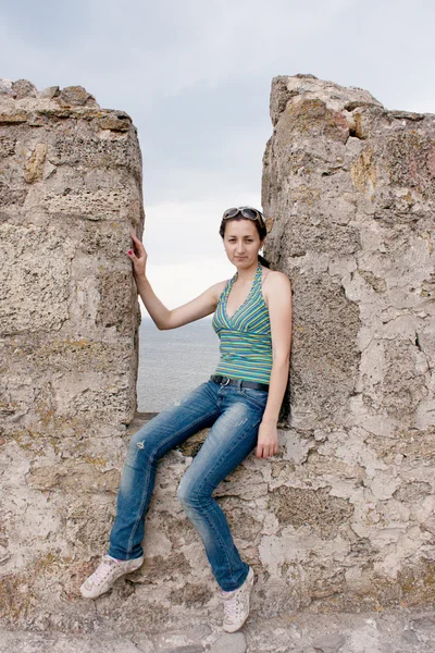 A girl sits in a niche of a stone wall — Stock Photo, Image