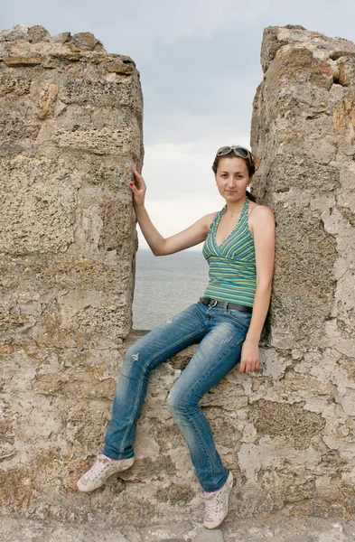 Una chica se sienta en un nicho de un muro de piedra — Foto de Stock