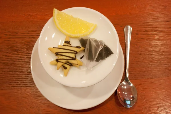 Tea bags, lemons, cookies, cup and spoon — Stock Photo, Image