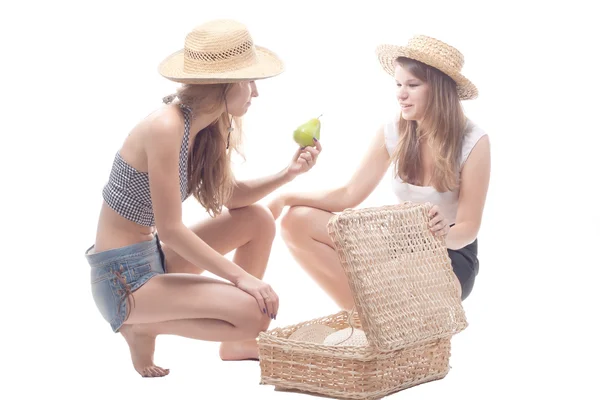 Duas meninas em chapéus de palha com uma mala de palha — Fotografia de Stock