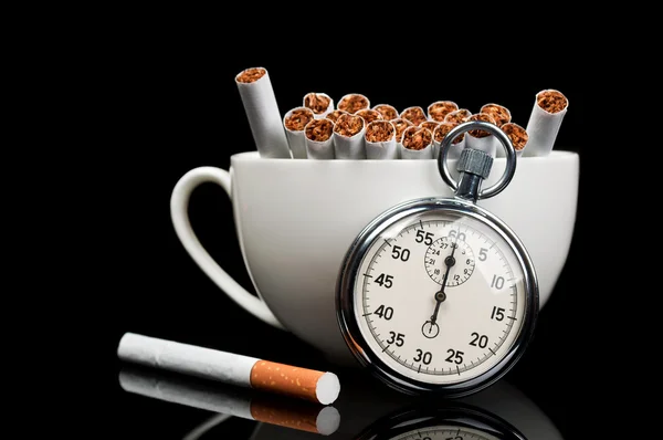 Beker vol sigaretten en stopwatch — Stockfoto