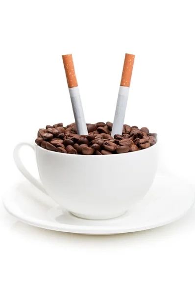 Full cup with coffee beans and cigarettes — Stock Photo, Image
