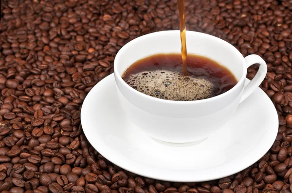 Белая чашка с кофе и кофе в зернах — стоковое фото
