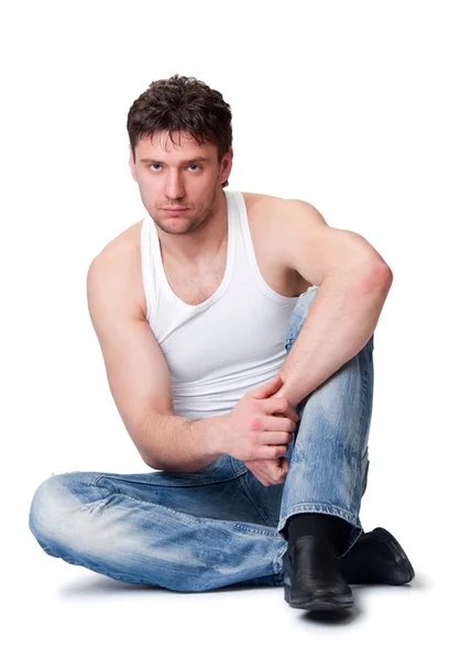 Hombre en jeans sentado sobre un fondo aislado —  Fotos de Stock