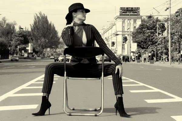 Mulher de terno sentada em uma cadeira em uma estrada — Fotografia de Stock