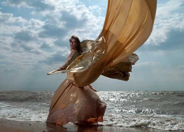 Kvinna i exotiska klänning stående på stranden — Stockfoto