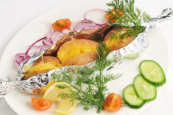 The baked potato in a foil with a garnish — Stock Photo, Image