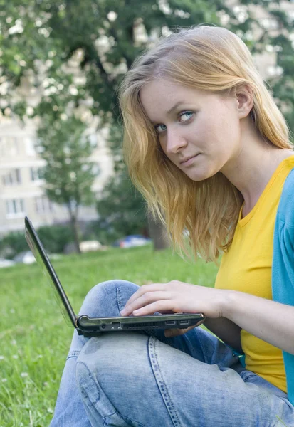 Красивая женщина с ноутбуком на зеленой траве — стоковое фото