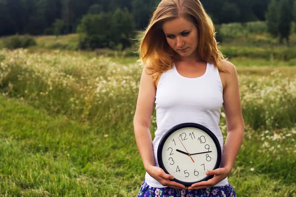 Jeune femme avec une horloge murale — Photo