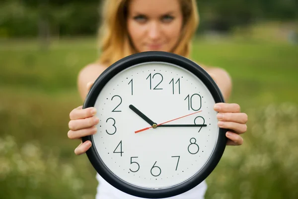 Young woman with a wall clock — Stock Photo, Image