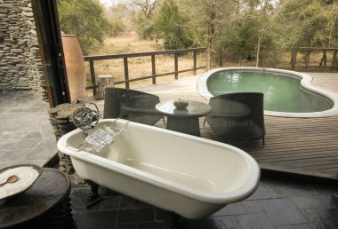 Bath with a view over a deck and a pool in Africa clipart