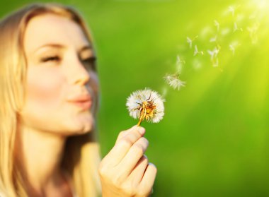 Happy beautiful girl blowing dandelion clipart