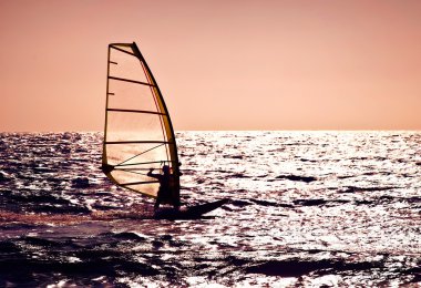 Windsurfer silhouette over sea sunset clipart