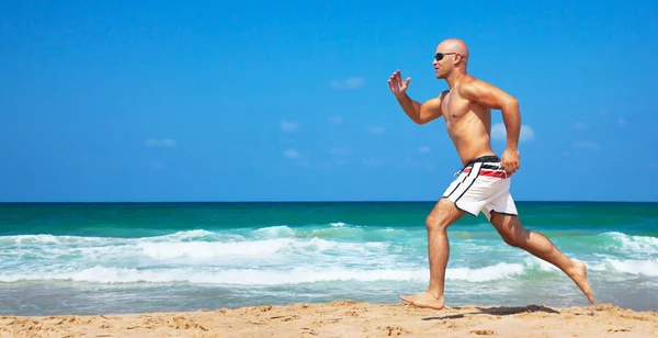 Zdrowy człowiek działa na plaży — Zdjęcie stockowe