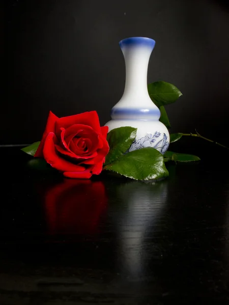 Mooie rode roos met vaas versierd met hints van zwarte tabel — Stockfoto