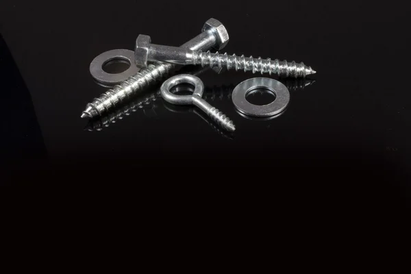 Two crossed screws and washers on a black background — Stock Photo, Image