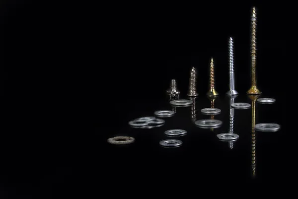 Screws and washers of various sizes on a black background — Stock Photo, Image