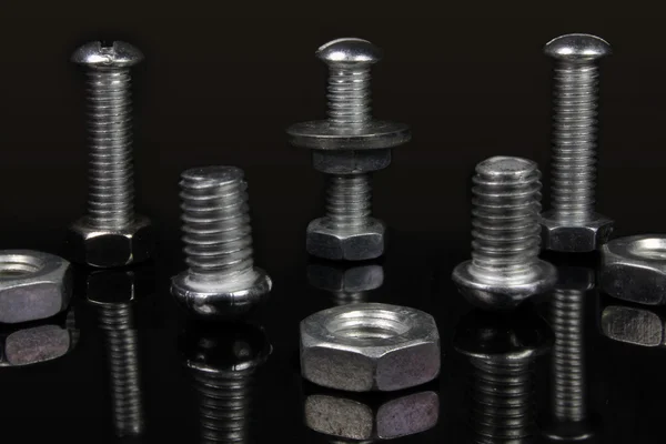Varios tornillos y tuercas sobre fondo negro — Foto de Stock