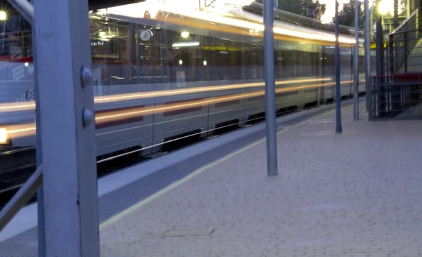 Suburban trein passeren van een station op volle snelheid — Stockfoto