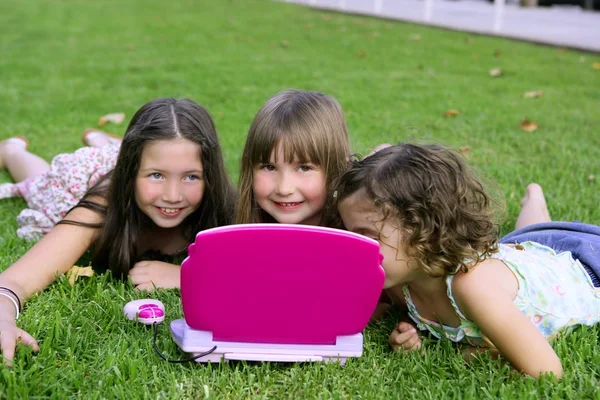Drie klein meisje spelen met speelgoed computer in gras — Stockfoto