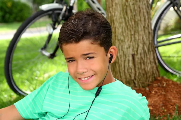Έφηβος που είναι χαμογελώντας αγόρι ακρόαση μουσικής ακουστικά χόρτο — Φωτογραφία Αρχείου