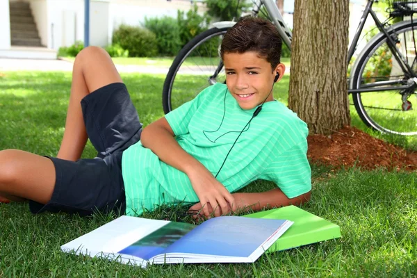 Adolescente sorrindo menino estudando livro jardim fones de ouvido — Fotografia de Stock