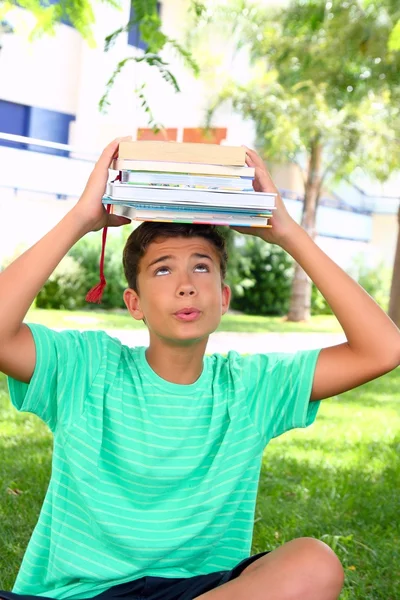Menino adolescente estudante segurando cabeça empilhados livros — Fotografia de Stock