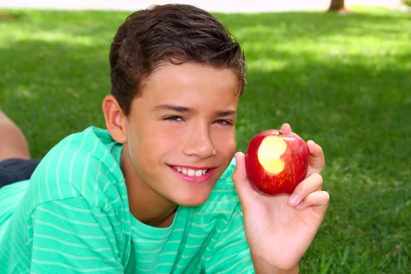男孩少年在花园草地上吃红苹果 — 图库照片