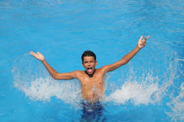 Niño adolescente salpicando agua abierta brazos piscina —  Fotos de Stock