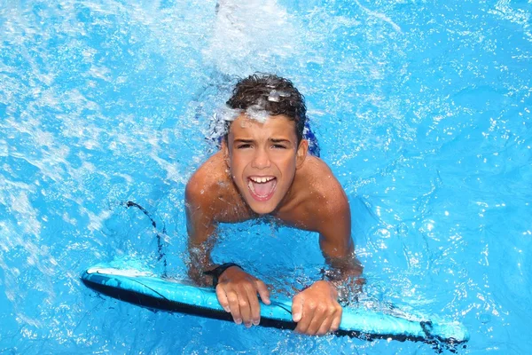 Jongen tiener surfplank spatten blauw water — Stockfoto
