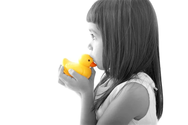 Маленькая девочка целует желтую утку для ванны — стоковое фото