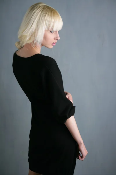 Mooie blonde profiel meisje grijze achtergrond — Stockfoto
