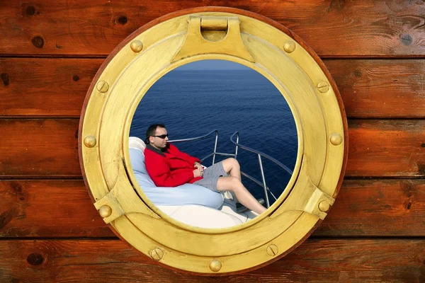 Man relaxed on bean bag over blue sea, round window — Stock Photo, Image