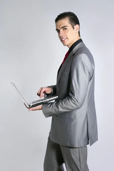 Uomo d'affari in tuta grigia che tiene il computer portatile — Foto Stock