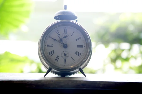 Old alarm bell clock at the window backlit — Stock Photo, Image