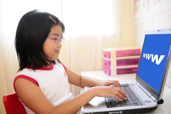 Ασιατικό κορίτσι παίζει με το φορητό υπολογιστή στο τραπέζι — Φωτογραφία Αρχείου